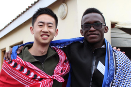 Daniel Zhang and Martin Lubowa pose for a photo while wearing a red and blue Swazi outfits.