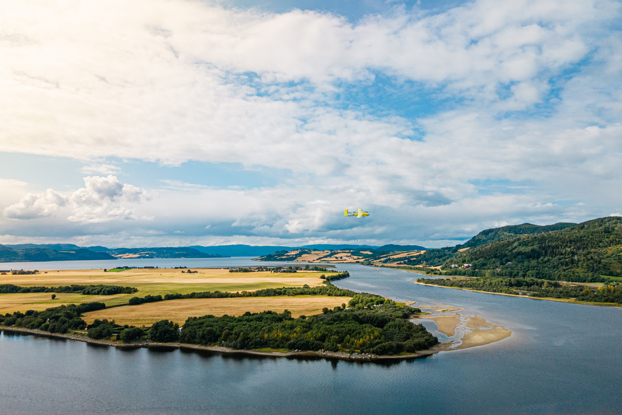 A winged drone flies over a wilderness area
